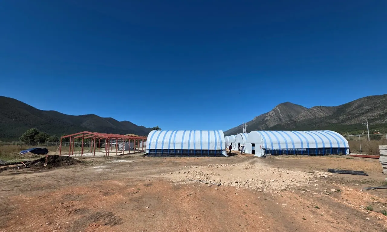 Invernaderos terminados y fábrica de sustratos en construcción, con la sierra al fondo
